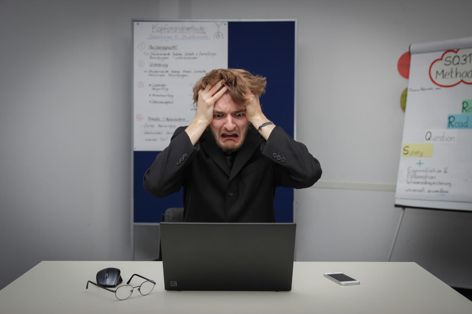 Stressed office worker holding his head at a laptop